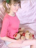 Child looking bimbo with ponytails is posing with her favorite teddy bear