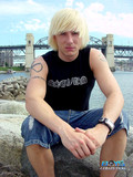 White haired young guy gets topless on the beach in the middle of the day