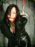 High heeled gagged brunette in black latex outfit gives strappado bondage a try