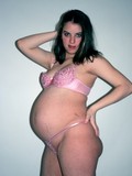 heavy-pregnant-brunette-with-big-belly-poses-in-pink-lingerie-showing-her-nipples