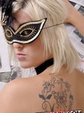 Blonde haired alt girl in black lace lingerie shows tattoo on her back