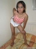 petite-girl-from-thailand-poses-in-diaper-and-top-on-her-bed-and-touches-herself