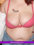 Fat woman in jean shorts takes off her white blouse and poses in red bra